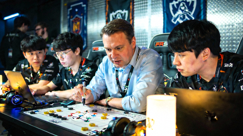 电竞比赛后台，教练与队员正在紧张地进行战术讨论